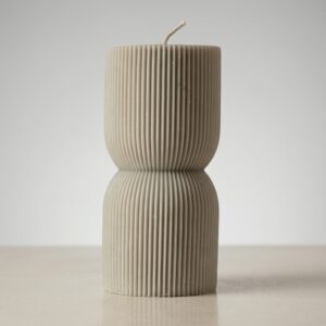 Vela artesanal decorativa con silueta entallada y textura acanalada de líneas verticales